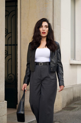a lady in a white top, a PU leather jacket and a pair of grey wide leg pants